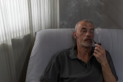 一位老人一边看报，一边用烟斗抽着烟草。