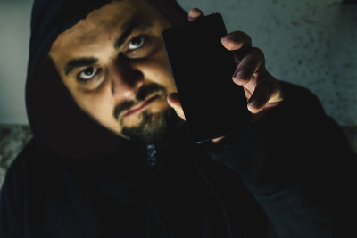 愤怒的黑客拿着黑屏手机。网络攻击的警告。Ransomware概念