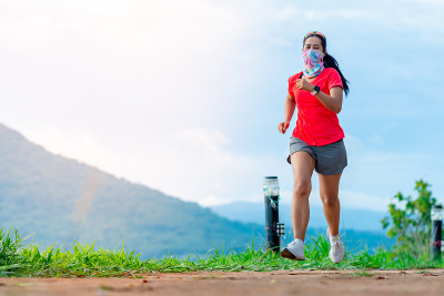 女跑步者穿着粉红色的运动服，在碎石地上练习跑步。在高山上带着快乐的心情，在晴朗的日子背后是山景。