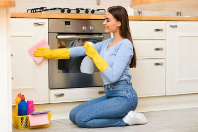 年轻女子用喷雾器清洁厨房家具