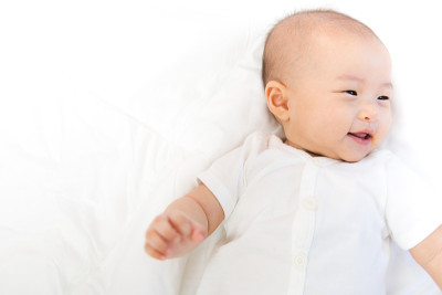 亚洲宝宝在房间里很开心。亚洲女婴躺在床上。