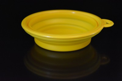 黄色折叠多功能橡胶板，一个碗与塑料边缘在黑色光滑表面。