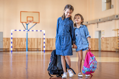 空空的学校体育馆里背着书包的小女孩们。