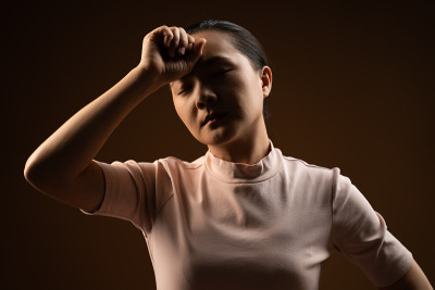 亚洲妇女生病头痛孤立站在米色背景。低调。