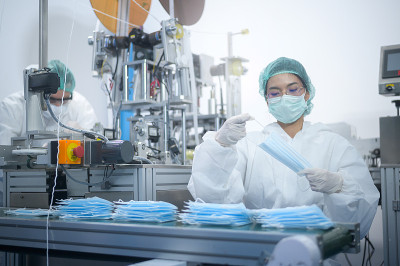 现代工厂生产外科口罩的工人，新冠病毒防护和医疗理念。