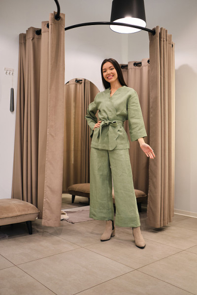 漂亮快乐的亚洲女孩在现代服装店的试衣间里愉快地看着镜头，试穿着时髦的西装