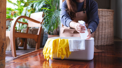 一名年轻女子从家里的清洁工具桶里捡起喷雾瓶