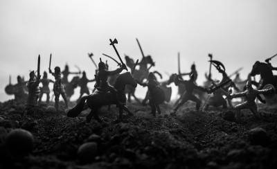 有骑兵和步兵的中世纪战斗场景。剪影的人物作为单独的对象，战斗之间的战士在日落雾蒙蒙的背景。有选择性的