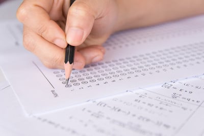 学生手持铅笔在答题纸和数学问题纸上写下选定的选项。学生考试做考试。学校考试