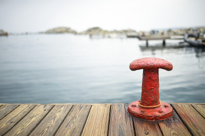 Red bollard with a mooring rope on the pier at the
