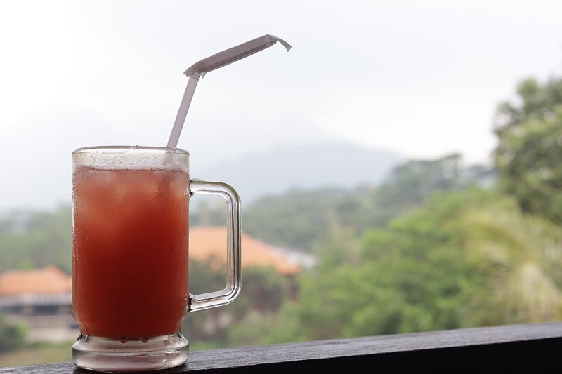 一杯冰茶，用一根塑料吸管，背景是山