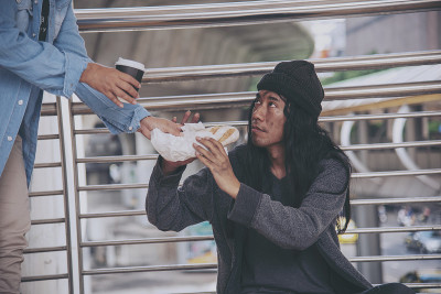 女人帮助无家可归的人贫穷的乞丐男人手拉着手要求钱的工作，希望帮助在无助的肮脏的城市坐在街道上。城市概