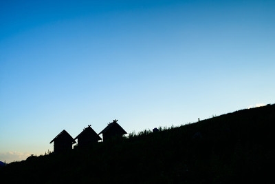 蓝天上剪影的房子和小山