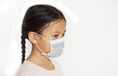 一个亚洲小女孩戴着白色背景的保护面具
