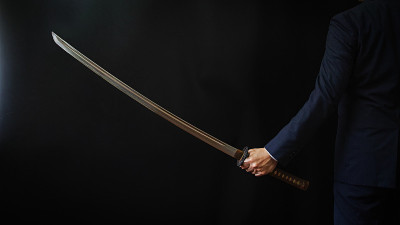 一个穿着西装，手持日本剑的男人