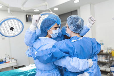 部分观点的努力工作的男性和女性医院团队在完整的防护服站在一起，在集体拥抱。