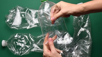 女性用手捏碎塑料瓶。垃圾分类回收理念