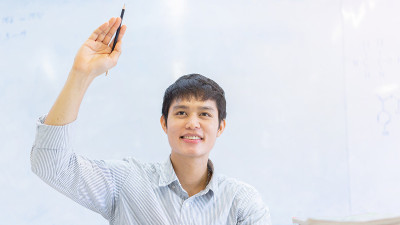 近年轻的亚洲大学生男子在课堂上举手问老师关于教育和人的观念的项目或考试