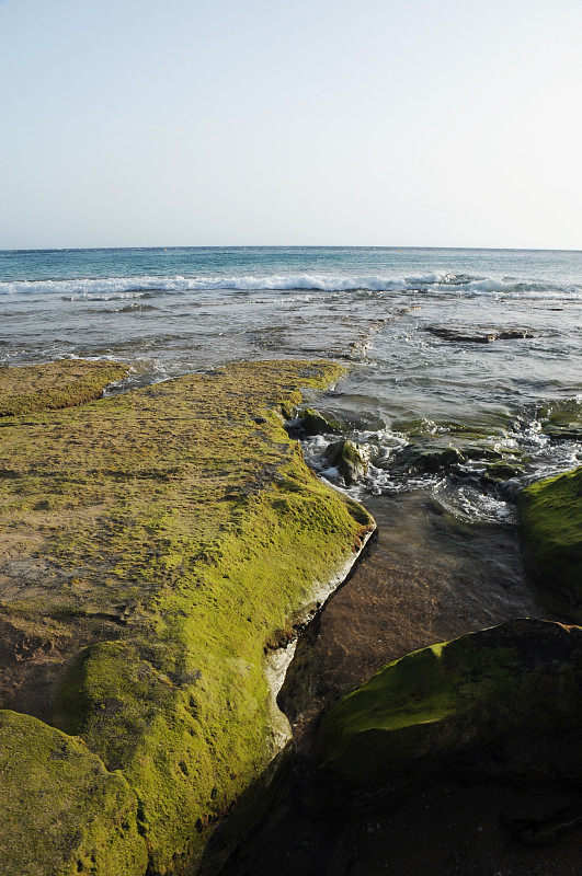 以悬崖和岩石为背景，海浪撞击它们，天空为背景