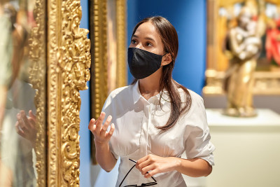 戴着防毒面具的女游客在历史博物馆里看照片。