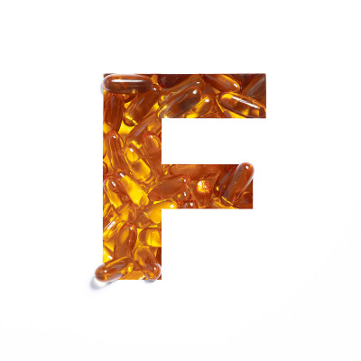 ω补充。油鱼丸和纸切割字母F孤立在白色上。药房的黄金字体