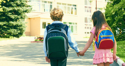 男孩和女孩把书包放在后面。两个小学生结伴而行。学校课程的开始。
