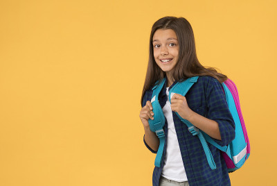 Schoolgirl posing with schoolbag at studio backgro