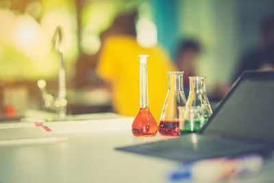 玻璃器皿化学科学实验室的桌子上和模糊的平板上模糊的学生在教室里