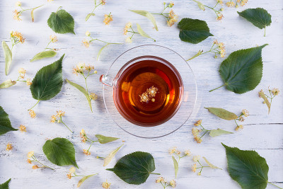 一杯菩提树茶，白木桌上放着菩提树花。