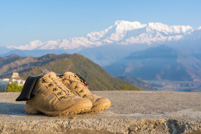 游客登山鞋和袜子以安纳普尔纳山脉雪峰为背景。登山和徒步旅行，旅游和旅游的概念。股票特写照片。