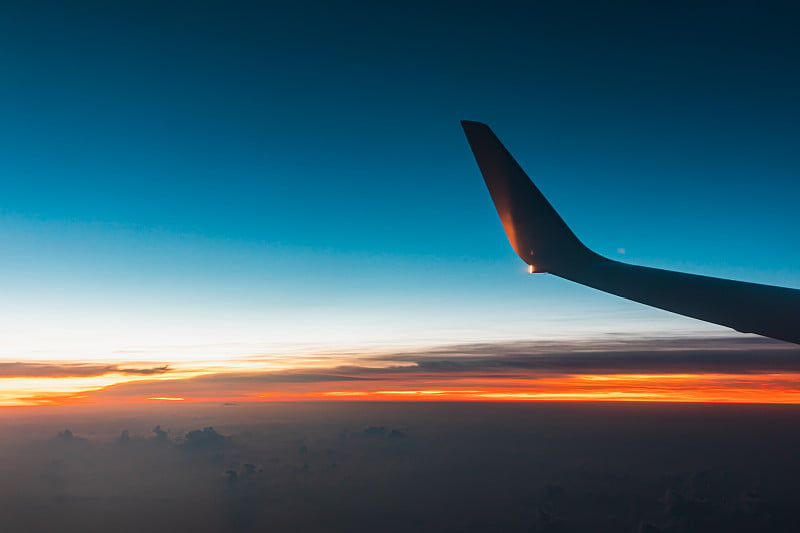 日落时飞机在云层上空飞行。