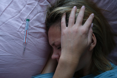一个年轻的女人躺在床上，头靠近水银温度计