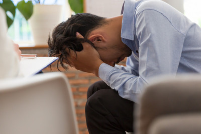 年轻的亚洲男子与专业的心理学家谈论他的问题，同时进行咨询和记录，以寻求建议和治疗