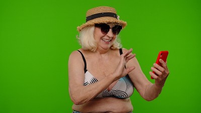 成熟的女性旅行者博主戴着太阳镜，自拍肖像照片，用智能手机视频通话