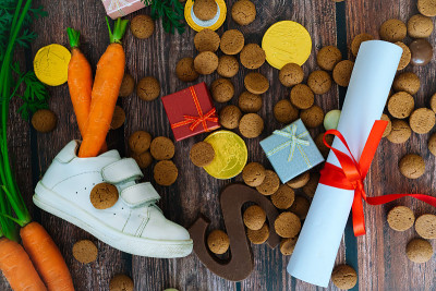 荷兰节日的Sinterklaas背景有儿童鞋、胡萝卜为圣诞老人的马、礼物、传统的蜜饯和巧克力信。平铺