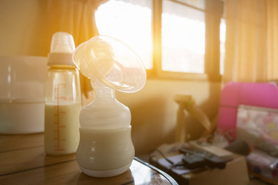 自动吸乳器，妈妈的母乳是新生儿最健康的食物。快乐的母亲和婴儿在卧室，家，复古的颜色