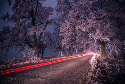 冬天的夜里，结冰的道路上有灯光的痕迹。