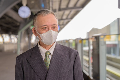 成熟的日本商人带着面具在空中火车站思考