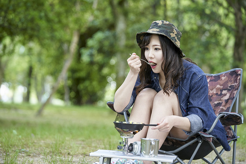 一个年轻的日本女人独自在营地做饭