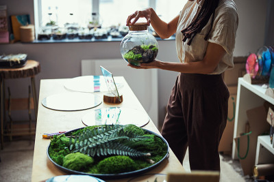 一个手里拿着花坛的女人站在桌子旁