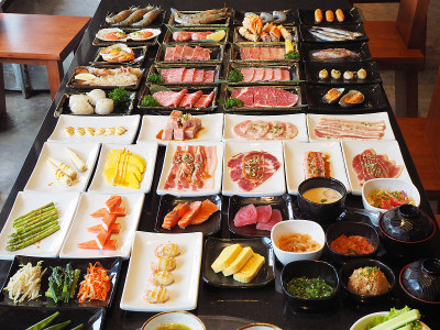 一盘盘生肉，如海鲜、牛肉、猪肉、蔬菜和蘸酱。