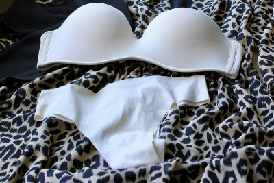 皮肤米色女性内衣:乳罩、内裤和香水躺在动物豹纹衣服的背景上。美丽、时尚的概念。基本的内衣。