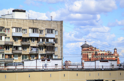 在其他多层住宅面板建筑和蓝天的背景下，住宅金属屋顶上的卫星天线和电线。屋顶上有很多电线