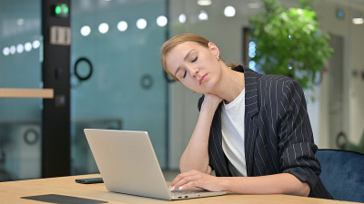 疲惫的年轻女商人与笔记本电脑脖子痛