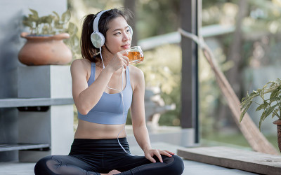 亚洲运动女性在家喝茶和听音乐