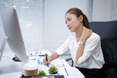 亚洲女性在办公室里工作很累。她想放松一下。