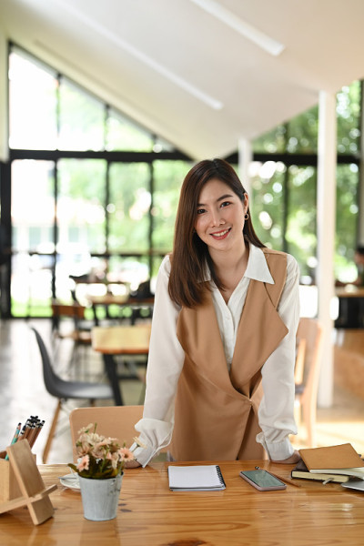 女秘书站在她的办公桌上，面带微笑。
