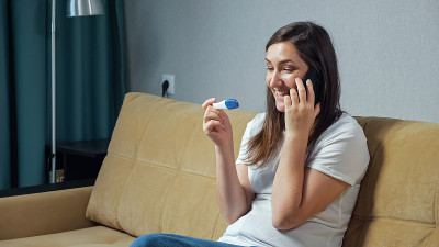 快乐的女人手里拿着验孕棒打电话