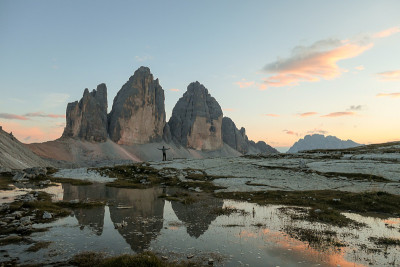 在意大利Dolomites的Drei Zinnen山，一个人在欣赏日落。山峰倒映在船桨上。群山被橙色