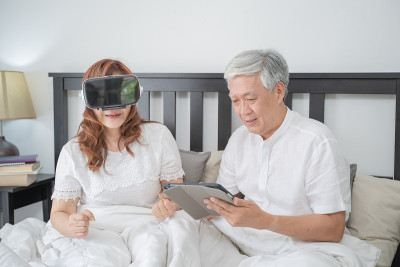 快乐亚洲老年夫妇生活科技设备概念，可爱的老年夫妇使用VR头盔在家